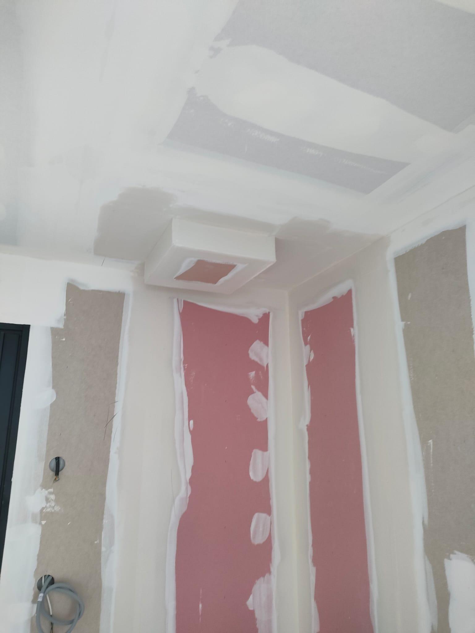 Plafond et plaques de plâtre murales en cours de finition avec joints enduits.