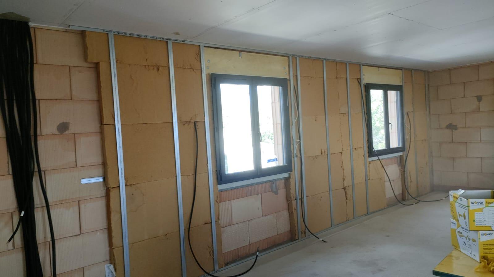 Panneaux isolants installés entre des montants métalliques autour de deux fenêtres.