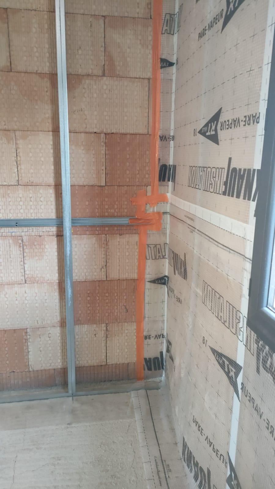 Mur en cours d'isolation avec panneaux isolants et ossature métallique visibles.